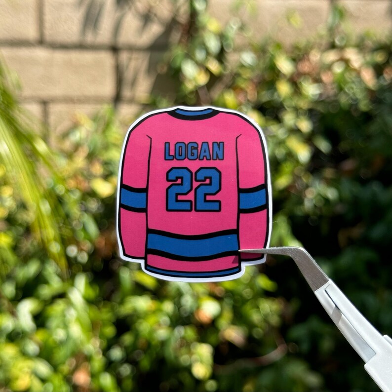 May include: Pink and blue hockey jersey sticker with the name "Logan" and the number "22" printed on the back.
