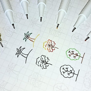 May include: A white sheet of paper with a grid pattern.  There are seven white pens with black tips and a brown pen with a black tip.  The pens are arranged in a row at the top of the page.  There are nine drawings of trees in different colors, including green, red, orange, and black.