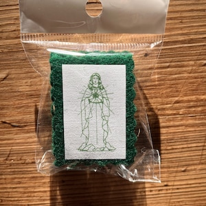 May include: A small green felt patch with a white square in the center. The white square has a line drawing of a person with a heart in their chest.