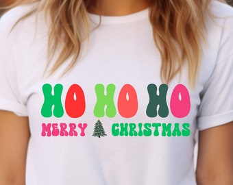 May include: White t-shirt with a green, red, and pink "Ho Ho Ho" graphic and the text "Merry Christmas" with a small green Christmas tree graphic.