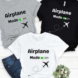 May include: Three t-shirts with the text "Airplane Mode on" and a silhouette of an airplane. The shirts are in gray, black, and white.