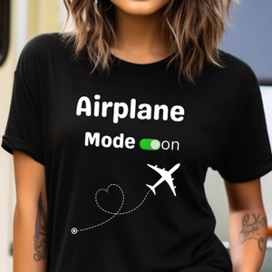 May include: Black t-shirt with white text that reads "Airplane Mode on" with a green toggle switch and a white airplane icon with a dotted line and a heart shape.