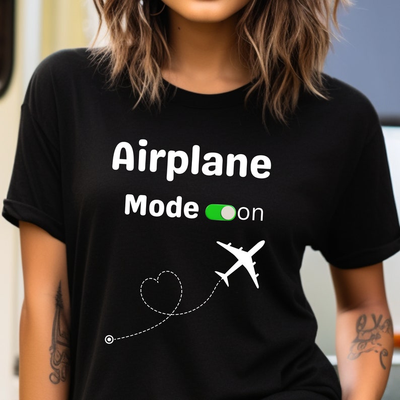 May include: Black t-shirt with white text that reads "Airplane Mode on" with a green toggle switch and a white airplane icon with a dotted line and a heart shape.