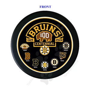 May include: A black and gold hockey puck featuring the Boston Bruins logo and the text "BRUINS 100 CENTENNIAL 1924 - 2024". The puck also includes smaller logos from various years.
