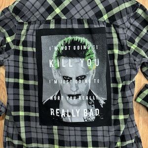 May include: A grey, black, and neon green checked shirt. The back displays a graphic of a character with green hair and the text "I'M NOT GOING TO KILL YOU, I'M JUST GOING TO HURT YOU REALLY BAD."