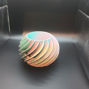 May include: A multi-coloured, 3D printed, decorative bowl with a spiral design. The bowl is made of plastic and has a smooth, glossy finish.