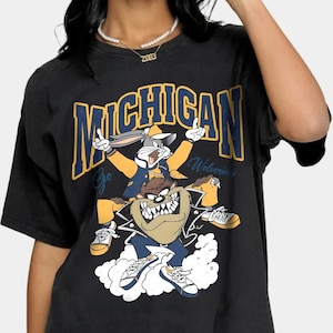 May include: Black t-shirt featuring a graphic of Bugs Bunny and Taz from Looney Tunes. The graphic includes the text "Michigan" and "Go Wolverines".
