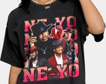 Puede incluir: Camiseta negra con un estampado gráfico del cantante Ne-Yo. El gráfico presenta varias imágenes de Ne-Yo en diferentes poses y atuendos. El texto "NE-YO" está impreso en letras grandes de color rosa en la parte inferior del gráfico.