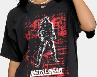 May include: Black t-shirt with a red and white graphic of a video game character, Metal Gear Solid.