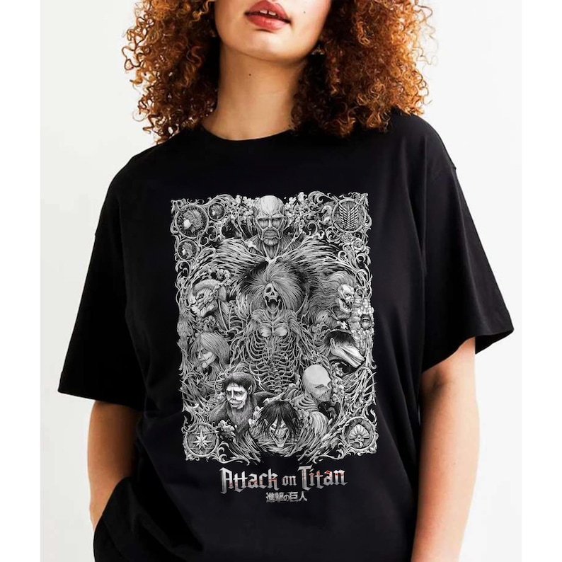 May include: Black t-shirt with a white graphic print of characters from the anime Attack on Titan. The graphic features a detailed illustration of the characters in a stylized design. The text "Attack on Titan" and "進撃の巨人" are printed below the graphic.
