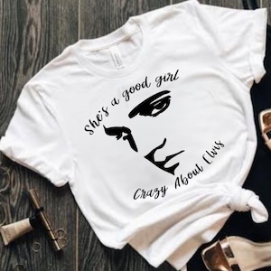 May include: White t-shirt with a black graphic of a woman's face and the text "She's a good girl Crazy About Elvis".