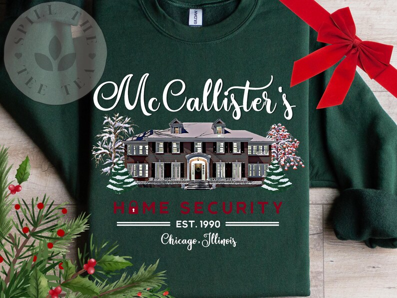 Puede incluir: Una sudadera de cuello redondo verde oscuro con un gr&aacute;fico blanco de una casa grande y &aacute;rboles nevados. El texto dice "McCallister's HOME SECURITY EST. 1990 Chicago, Illinois" en letras blancas y rojas, con un lazo rojo en la parte superior derecha.