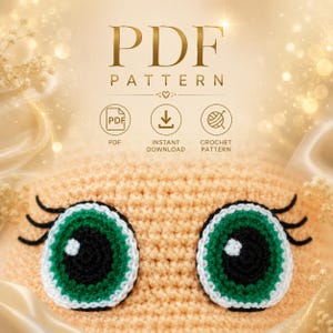 May include: A close-up of a crocheted item with large, green and white eyes and black eyelashes. The item is peach-coloured and the image has the text "PDF PATTERN" at the top, with icons for PDF, instant download, and crochet pattern.