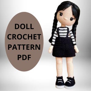 Peut inclure: Un modèle de poupée au crochet en PDF. La poupée porte une chemise à rayures noires et blanches, une robe de salopette noire et des chaussures noires. La poupée a les cheveux noirs et une expression douce.