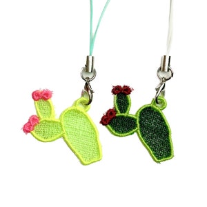May include: Two cactus-shaped phone charms with pink and red flowers. One charm has a green cactus with a light green cord. The other charm has a dark green cactus with a white cord.