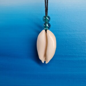 May include: A white cowrie shell pendant necklace with teal blue beads on a black cord.