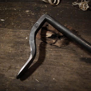 Könnte beinhalten: Ein gebogenes Werkzeug aus Metall mit einem Griff und einem Haken am Ende. Das Werkzeug ist aus dunklem Metall und hat eine Markierung am Griff, auf der "HP" steht.