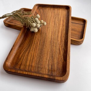 Könnte beinhalten: Zwei rechteckige Holztabletts aus dunkelbraunem Holz mit natürlicher Holzmaserung. Die Tabletts sind übereinander gestapelt.