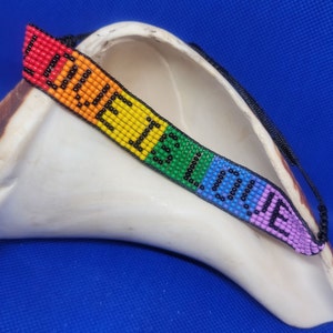 May include: A rainbow beaded bracelet with the word "LOVE" spelled out in black beads.