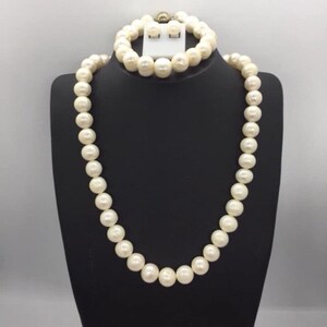Puede incluir: Un conjunto de joyas de perlas blancas, que incluye un collar, una pulsera y pendientes. Las perlas son redondas y lisas, y las joyas están hechas de materiales de alta calidad.