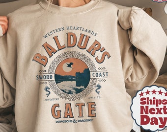 May include: A beige sweatshirt with a vintage-style graphic design featuring the text "Baldur's Gate" and a scene of a castle on a cliff with a bird flying overhead. The text "Western Heartlands" and "Dungeons & Dragons" are also included in the design.