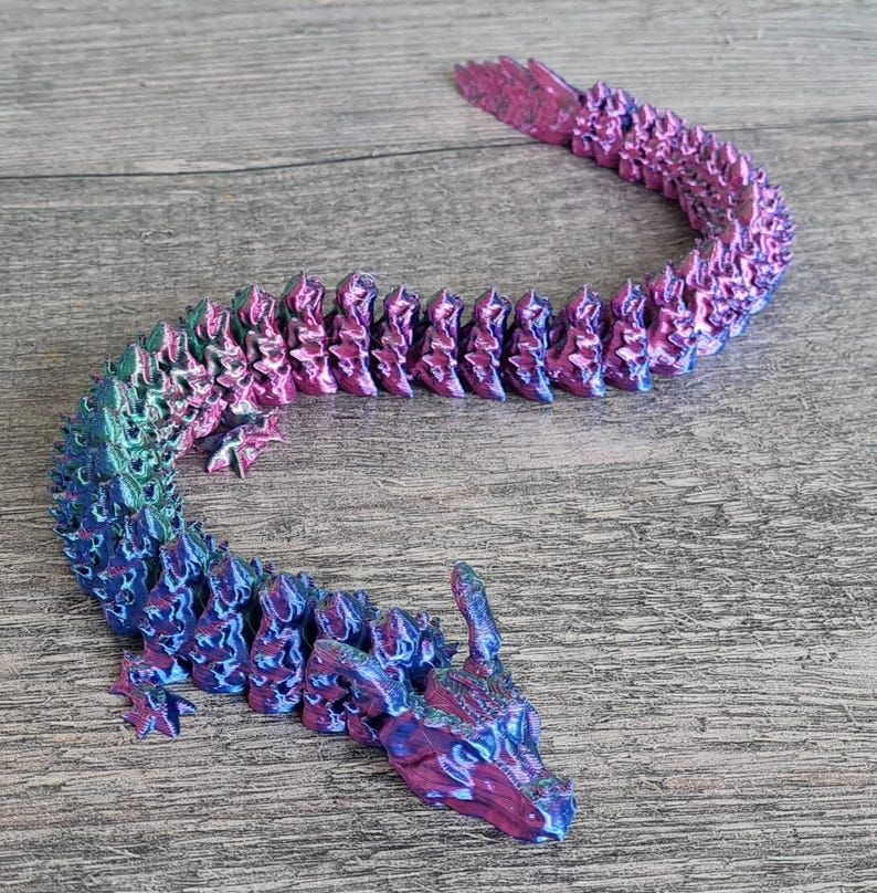 May include: A 3D printed dragon figurine with a segmented body, iridescent blue and pink paint, and a detailed head with horns.