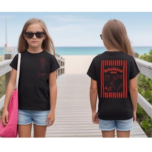 May include: A black t-shirt featuring a red graphic of an ice cream cone and the name Luisa on the front. The back displays a red rectangular frame with vertical stripes, the text Schulkind 2026, and icons of a backpack, ABC, pencil, and scissors.