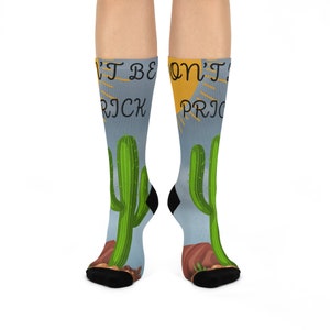 May include: A pair of blue and green socks with a cactus and sun graphic. The socks have the text "Don't be a prick" on one sock and "Don't be a pric" on the other sock.