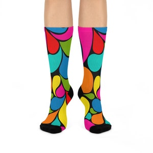 May include: A pair of colorful socks with a black background and a pattern of teardrop shapes in shades of red, orange, yellow, green, blue, and pink.
