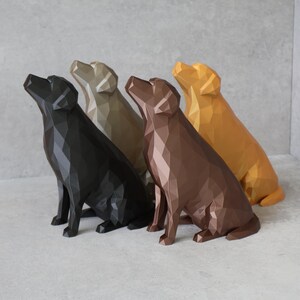 May include: Four geometric dog sculptures in black, tan, brown, and gold. The dogs are in a sitting position, looking upwards. The sculptures have a modern, polygonal design and are arranged in a row.