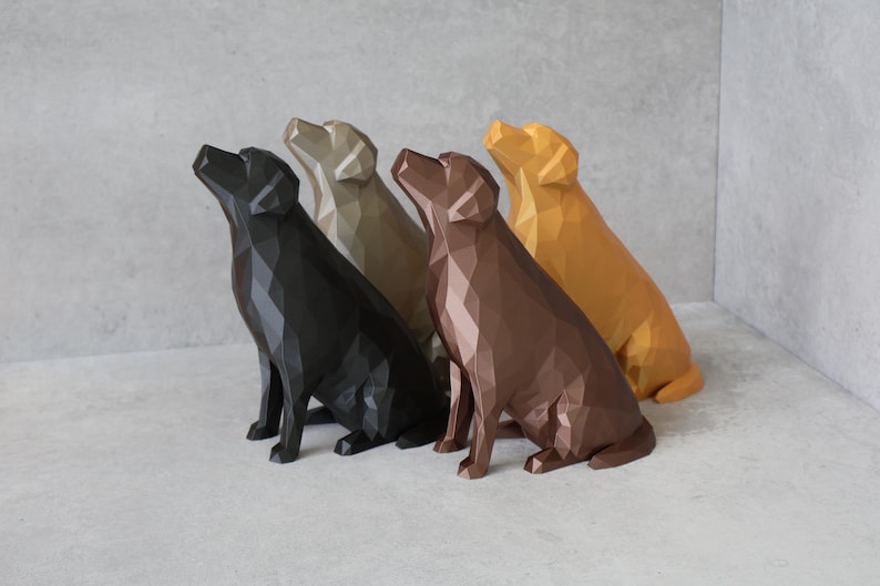 May include: Four geometric dog sculptures in black, tan, brown, and gold. The dogs are in a sitting position, looking upwards. The sculptures have a modern, polygonal design and are arranged in a row.