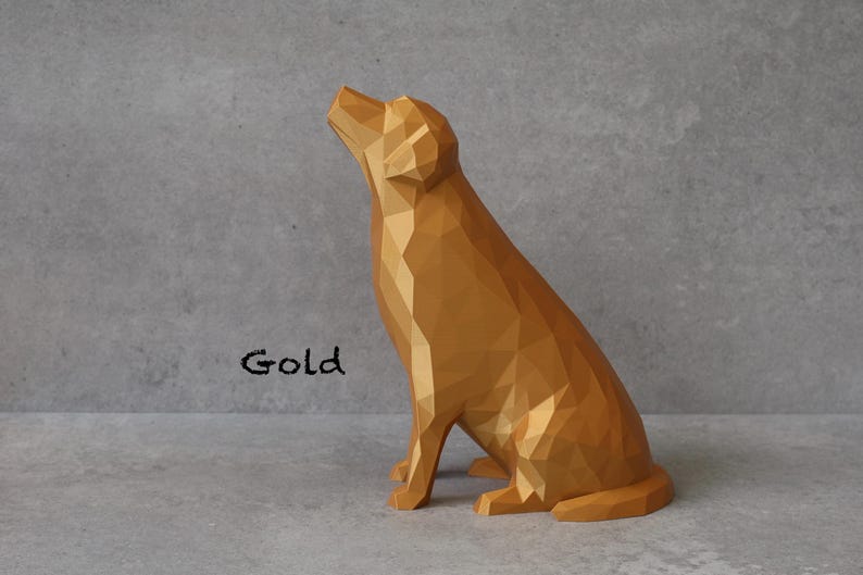 May include: A gold-colored, geometric dog sculpture in a sitting position, with its head tilted upwards. The word "Gold" is written in black script below the dog. The sculpture has a faceted design.