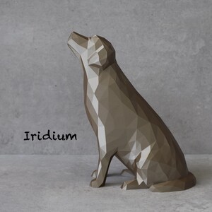 May include: A geometric, polygonal dog sculpture in a seated position, with its head tilted upwards. The sculpture is a muted, metallic brown color and is set against a gray backdrop. The word "Iridium" is printed in black.