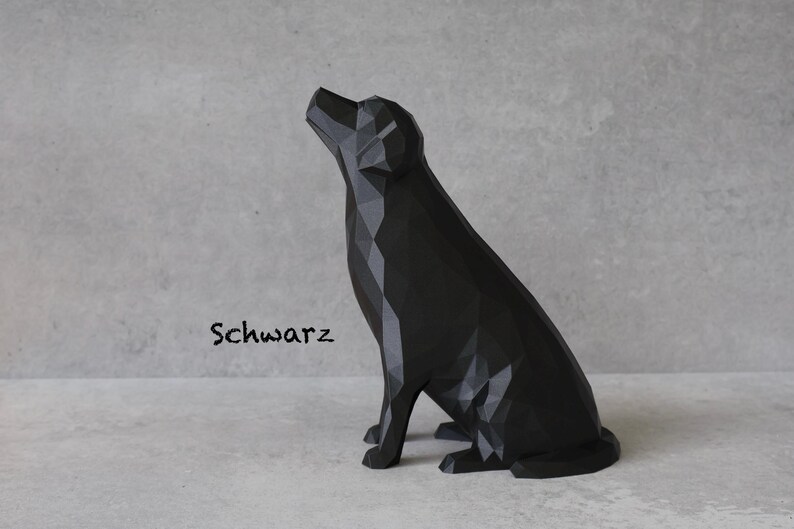 May include: A black geometric dog sculpture in a sitting position, with its head tilted upwards. The word "Schwarz" is written in a script font on the left side of the image. The sculpture is on a light gray surface.