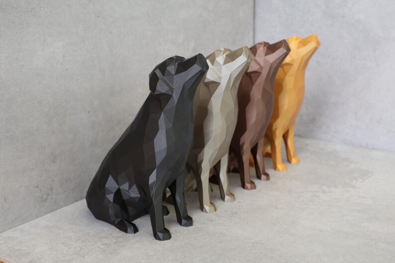 May include: A row of five geometric dog sculptures in shades of black, gray, beige, brown, and gold. The dogs are in a sitting position with their heads tilted upwards. The sculptures are displayed on a light gray surface.