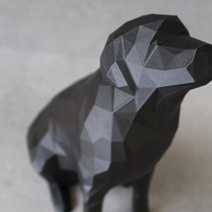 May include: A black geometric dog sculpture. The dog is depicted in a low-poly style, with many flat, angled surfaces creating its form. The sculpture is made of a matte black material and stands on four legs, with its head raised.