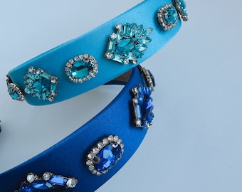 Può includere: Due fasce per capelli in raso con decorazioni di gioielli blu e turchese. La fascia in alto è blu chiaro con gioielli turchesi, e la fascia in basso è blu scuro con gioielli blu.