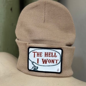 May include: A beige knitted beanie with a black and white patch that says "The Hell I Won't" in red lettering.