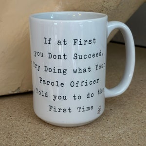 May include: White ceramic mug with a black text that reads: "If at First you Dont Succeed, Try Doing what Your Parole Officer Told you to do the First Time."