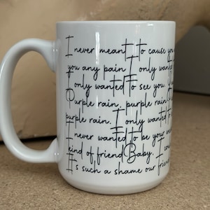 May include: White ceramic mug with a black handwritten quote that reads "I never meant to cause you any pain only wanted to see you. Purple rain, purple rain. I only wanted to be your kind of friend Baby. It's such a shame our friendship..."