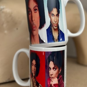May include: Two white ceramic mugs with images of Prince on them. The top mug has a blue background and the bottom mug has a red background.