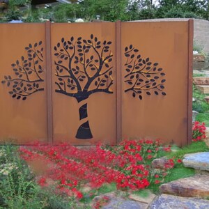 Könnte beinhalten: Ein rostiger Metallzaun mit einem ausgeschnittenen Design eines Baumes. Der Zaun besteht aus drei Paneelen und ist vor einem Hintergrund aus grünem Gras und Steinstufen platziert.