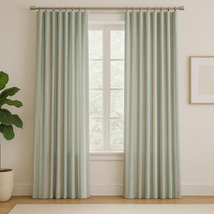 May include: Two striped window curtains in a light blue, beige, and white color scheme. The curtains are hanging from a silver rod in front of a window. The curtains have vertical stripes and are made of a textured fabric. A potted plant is visible on the left.