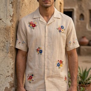 Puede incluir: Conjunto de camisa y pantal&oacute;n corto de lino beige con bordados florales coloridos. La camisa de manga corta tiene cuello de solapa y cierre de botones. El pantal&oacute;n corto tiene un dise&ntilde;o floral a juego en el dobladillo. Ideal para climas c&aacute;lidos.