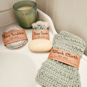 May include: Three crocheted cotton washcloths in a bathroom setting. The washcloths are labeled "Face Scrubbie", "Soap Saver", and "Wash Cloth". Each washcloth is made from 100% cotton and hand-made by watermelon tree.