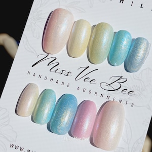 Könnte beinhalten: Ein Set aus zehn schimmernden Press-On-Nägeln in Pastellfarben, darunter Rosa, Gelb, Blau und Grün. Die Nägel sind oval geformt und haben ein schimmerndes Finish. Die Karte trägt die Aufschrift "Miss Vee Bee Handmade Adornments."