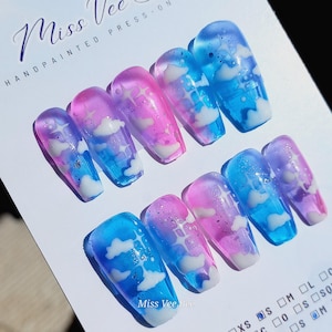 May include: Set of ten press-on false nails with a blue and pink ombre design featuring white clouds. The nails are hand-painted and have a glossy finish.  "Miss Vee Ree" is written on the card.