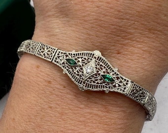 Antieke Art Deco armband van 14 karaat witgoud met filigraanwerk, smaragden en diamanten, 17 cm lang, fijne vintage sieraden.