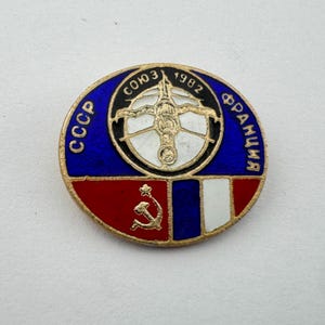 May include: A white ceramic mug with a black handle and the text "But First, Coffee" in a black, handwritten-style font. The mug is on a white surface.