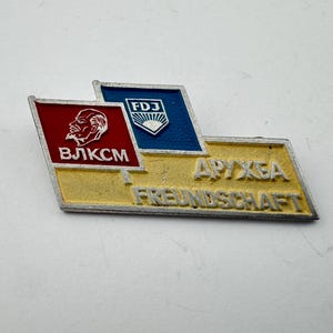 May include: A white ceramic mug with a black handle and the text "But First, Coffee" in a black, bold font. The mug is sitting on a wooden surface. The mug is approximately 4 inches tall.